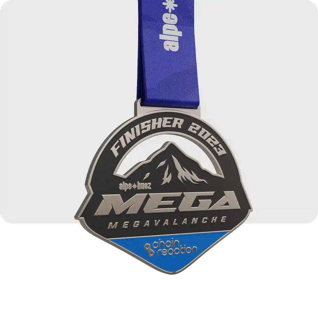 médaille gravée en métal, de couleur noir, bleu foncé et gris. En son centre se trouve une des montagne de l'Alpe d'Huez avec en dessous le nom de la course. 