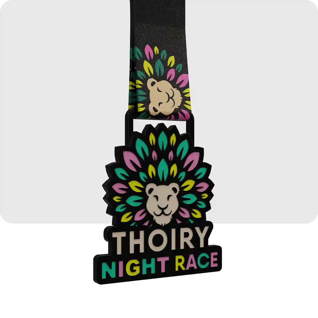 médaille gravée en métal de couleur noir, vert, turquoise et rose pale. 
avec en son centre une tête de lion. ainsi que le nom de l'évènement. 
