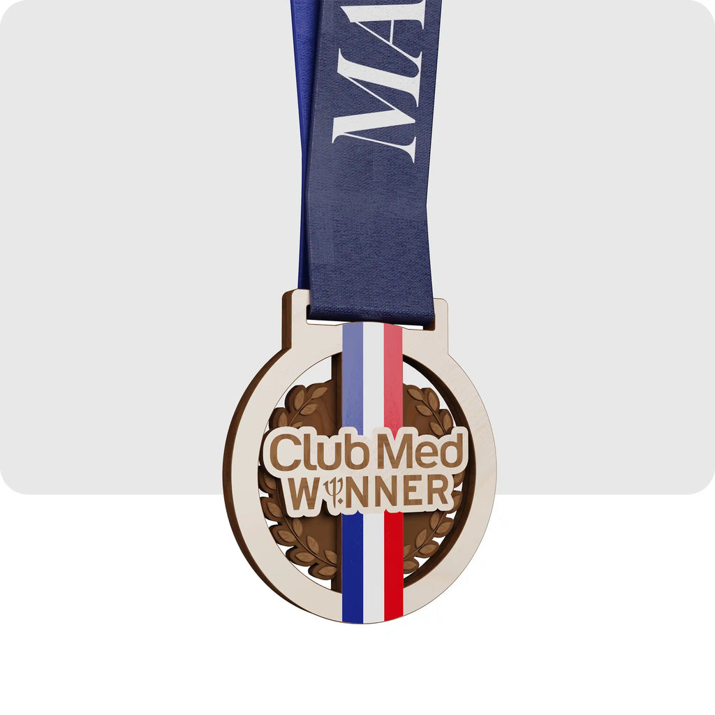 Médaille en bois Club Med Winner avec ruban bleu et motif tricolore rouge blanc bleu.