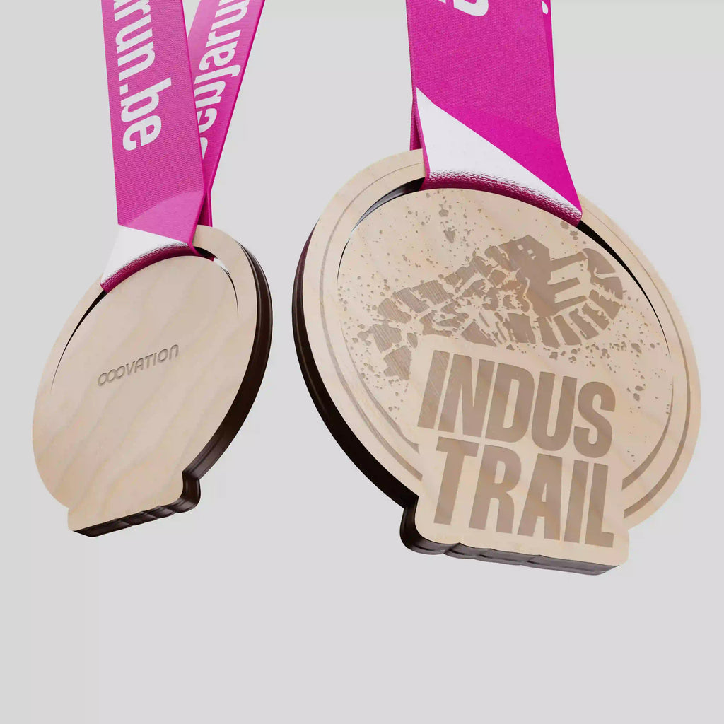 Médaille en bois Indus Trail avec empreinte de semelle gravée et ruban rose vif.
