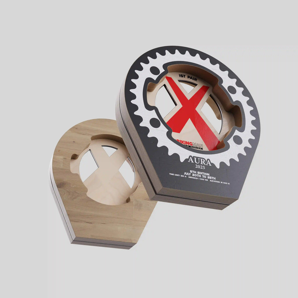 Trophée en bois BikingMan AURA 2025 en forme de pignon de vélo avec design ajouré et logo rouge.